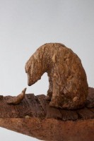 Waiting for the Ferryman, Ceramic, 27.5H x 22W x 6.5D Inches A ceramic sculpture by Michael Hermesh that depicts five passengers carrying suitcases standing on the backs of birds of prey that are riding in a boat